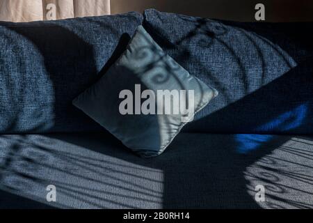 Cuscini blu scuro con ombre da belle finestre. Luce finestrino. Immagine interna dello sfondo astratto. Foto Stock