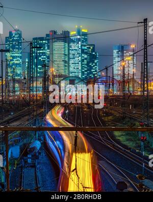 Treno di guida di fronte alla stazione centrale di Francoforte sul principale di fronte allo skyline, illuminato con colori vivaci, Francoforte, Assia, Germania Foto Stock