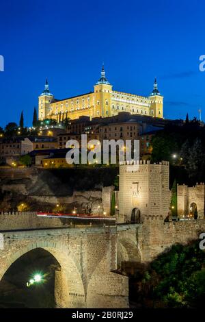 Porta del Ponte, Ponte dell'Alcantara, Puente del Alcantara, sul fiume Tajo, con Alcazar de Toledo, vista notturna, Toledo, Castilla-la Mancha, Spagna Foto Stock