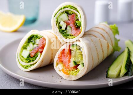 Avvolgete il sandwich, arrotolate con salmone di pesce e verdure. Sfondo grigio. Primo piano. Foto Stock