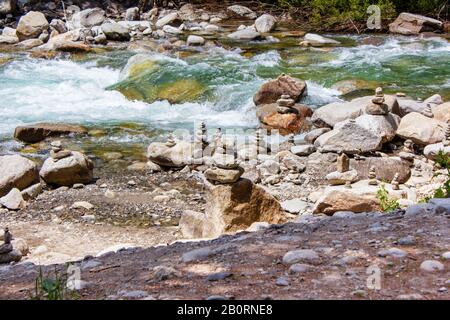 Armonia, equilibrio e semplicità. Una piramide di pietra sullo sfondo dell'acqua del fiume. Ciottoli di poise semplici, zen rock. Blu, vita. Foto Stock