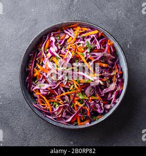 Insalata di cavolo rosso, insalata di cavolo in una ciotola. Sfondo grigio. Primo piano. Vista dall'alto. Foto Stock