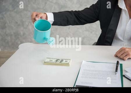 Acqua Che Si Riversa sulle banconote in dollari sul posto di lavoro. Foto Stock