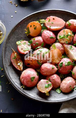 Primo piano di rafano arrostito su piatto su piatto scuro. Concetto vegetariano di cibo vegano. Foto Stock