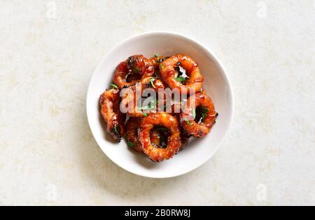 Chiudete gli anelli di cipolla avvolti con pancetta nel recipiente sopra uno sfondo di pietra chiaro e con spazio libero. Vista dall'alto, piatto Foto Stock