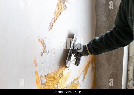 Lavoratore che sparge Malta su rete di fibra di vetro (rinforzando maglia). Incollaggio della rete di rinforzo in costruzione. Foto Stock