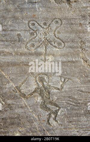 Petroglyph, scultura in roccia, di un guerriero che porta con una spada e uno scudo rotondo e indossa un casco alogeno che balla intorno alla cosiddetta Rosa Camuniana. Foto Stock