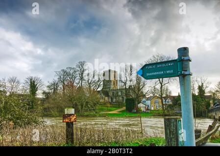 Segnale per la via pubblica di collegamento a Sharnbrook, Bedfordshire dal ponte Felmersham, con il fiume Great Ouse e la chiesa di St Mary sullo sfondo Foto Stock