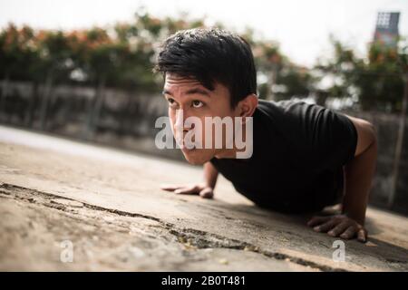 Immagine ravvicinata di un giovane sportivo che fa push-up all'esterno Foto Stock