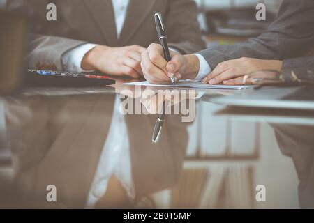 Due femmina commercialisti controllo finanziario o di conteggio dal reddito calcolatrice per forma fiscale e le mani di close-up. Internal Revenue Service inspector Foto Stock