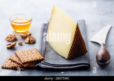 Formaggio duro, Manchego con noci, miele e cracker su sfondo grigio. Primo piano. Foto Stock