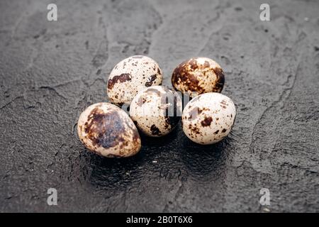 Uova di quaglia su uno sfondo nero. Parecchie uova di quaglia giacciono su una pietra nera sullo sfondo Foto Stock