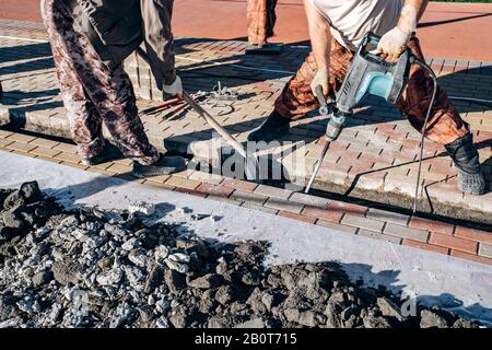 I lavoratori di cui pavimentazione in lastre. Due lavoratori laici di lastre per pavimentazione. Foto Stock