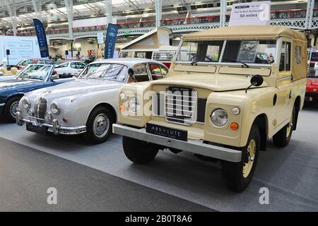 Automobili britanniche classiche in mostra al London Classic Car Show che ha aperto oggi a Olympia Londra, Regno Unito. Il veicolo più vicino è una berlina sportiva da 2,4 litri Jaguar MkII 1960 accanto a una Land Rover serie 3 SWB Soft Top del 1973. Oltre 500 delle più belle automobili e marchi classici del mondo, del valore di £70 milioni, sono in mostra allo spettacolo che va dai tour vintage prima della guerra ad un concept car moderno. Lo spettacolo porta in circa 20.000 visitatori, che vanno da gravi teste di benzina a persone che amano solo veicoli belli e classici. Foto Stock