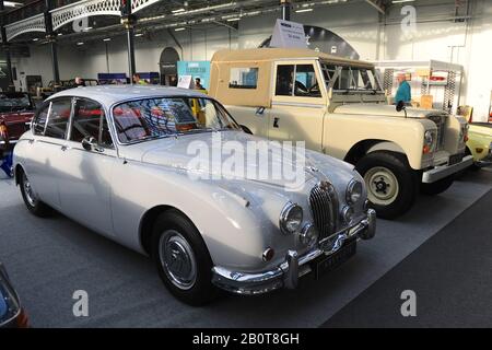 Due classiche auto britanniche in mostra al London Classic Car Show che ha aperto oggi ad Olympia Londra, Regno Unito. Il veicolo più vicino è una berlina sportiva da 2,4 litri Jaguar MkII 1960 accanto a una Land Rover serie 3 SWB Soft Top del 1973. Oltre 500 delle più belle automobili e marchi classici del mondo, del valore di £70 milioni, sono in mostra allo spettacolo che va dai tour vintage prima della guerra ad un concept car moderno. Lo spettacolo porta in circa 20.000 visitatori, che vanno da gravi teste di benzina a persone che amano solo veicoli belli e classici. Foto Stock