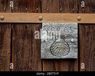 Conchiglia capesante su una porta di legno a Conques, dipartimento Aveyron, Occitanie, Francia Foto Stock