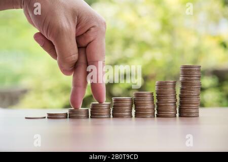 Dita che camminano su stack di monete o stack di denaro Foto Stock