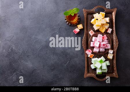 Assortimento di delizie turche su un autentico vassoio con bicchiere di tè. Sfondo scuro. Vista dall'alto. Spazio di copia. Foto Stock