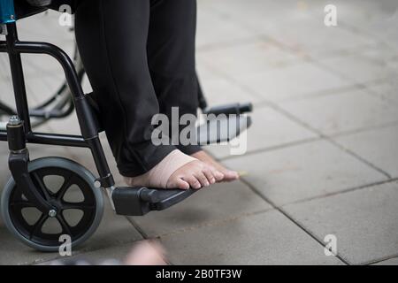 Primo piano piedi anziani dolore seduto su sedia a rotelle Foto Stock