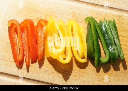 Peperoni a colori misti tritati su tagliere Foto Stock