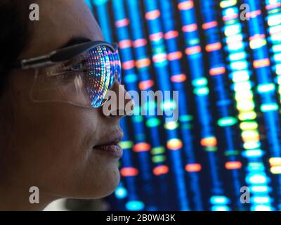 Ricerca genetica, scienziato femminile che osserva un profilo di DNA di un campione umano su uno schermo del laboratorio. Foto Stock