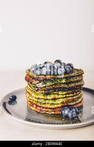 Frittelle sane e facili da frullare, realizzate con spinaci, latte di cocco, banane e avena con mirtilli. Colazione vegetariana e senza glutine Foto Stock