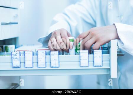 Primo piano del farmacista accanto a un cassetto con medicinali in farmacia. Foto Stock