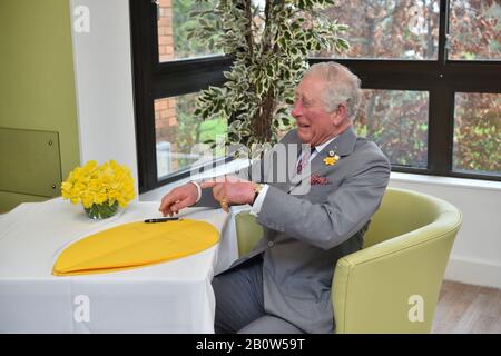 Il Principe di Galles firma un petalo come parte del Grande appello di Daffodil durante una visita all'Hospice Marie Curie a Cardiff e alla vale, Galles. Foto Stock