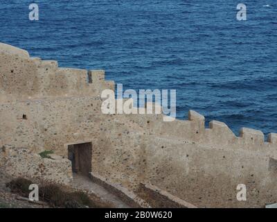 Muro di pietra della città murata di Monemvasia, Laconia, Peloponneso, Grecia, contro un mare blu. Foto Stock