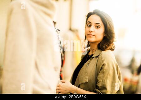 Ritratto di giovane donna con lunghi capelli castani che indossano cappotto beige, guardando la macchina fotografica. Foto Stock