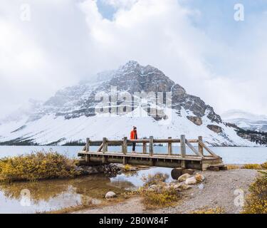 Hiker attraversando il ponte sul torrente in autunno, Bow Lake, Canadian Rockies, Alberta, Canada Foto Stock