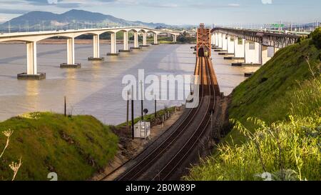 Benicia in California, arrugginita ole ponte e binari ferroviari, una grande giustapposizione di vecchio vs nuovo. Foto Stock