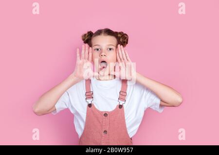 La bambina urla o esprime emozioni su sfondo rosa Foto Stock