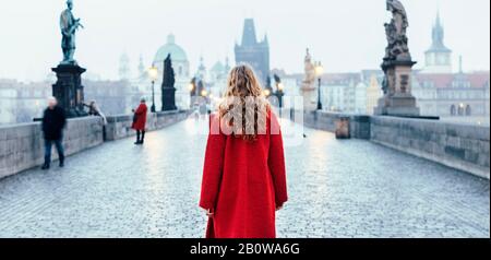 Turista femminile a piedi da solo sul Ponte Carlo durante la mattina presto a Praga, capitale della Repubblica Ceca Foto Stock