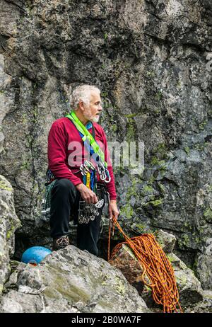 Un ritratto di un uomo maturo scalatore di roccia mentre si prepara per una scalata di roccia. Foto Stock
