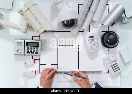 Architetto disegno Blueprint con varie apparecchiature di sicurezza sulla scrivania Foto Stock