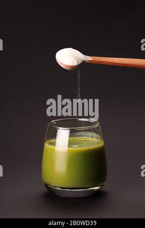 Succo verde con un cucchiaio di proteine o di collagene. Integratore alimentare concept Foto Stock
