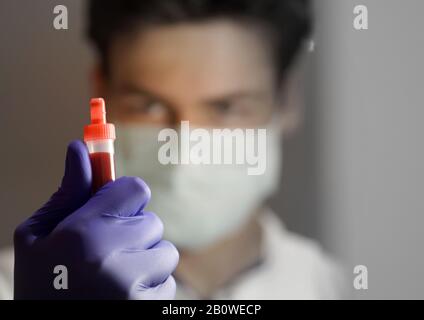 Chiusura di un campione di sangue tenuto dal personale del laboratorio medico in background Foto Stock