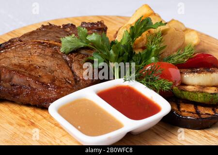 manzo alla griglia con pomodoro. Due salse e verdure. Foto verticale Foto Stock