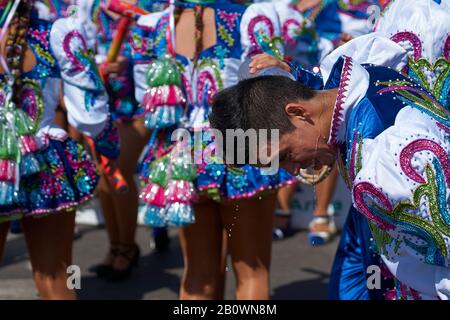 Membro maschile di un gruppo di ballo di caporales che si raffredda mentre si esibisce all'annuale Carnaval Andino con la Fuerza del Sol ad Arica, in Cile. Foto Stock