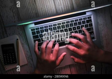 hacker con cappuccio che sigillano i dati dal portatile di notte Foto Stock