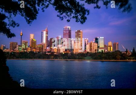 Skyline della città di Sydney attraverso il porto al tramonto, Australia Foto Stock