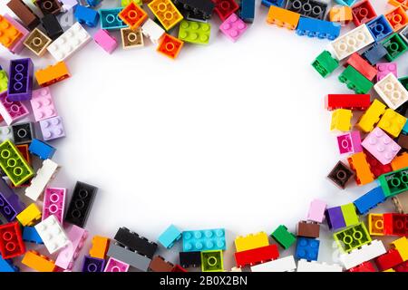 Primo piano di un mucchio ordinato di colorati mattoni Lego visto dall'alto con posto per il testo al centro. Isolato su sfondo bianco, spazio di copia. Foto Stock