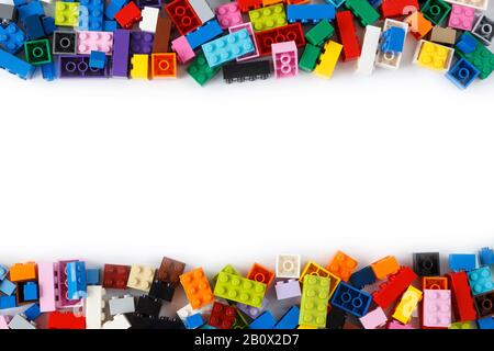 Primo piano di un mucchio ordinato di colorati mattoni Lego visto dall'alto con posto per il contenuto o il testo al centro. Isolato su bianco. Spazio di copia. Foto Stock