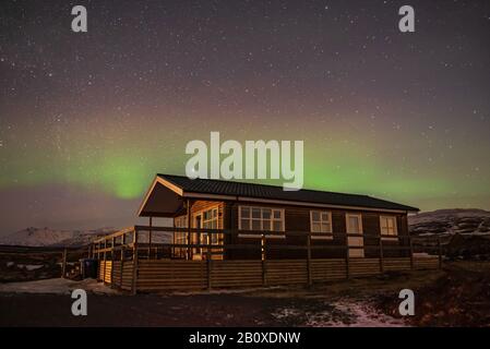Cottage sotto il cielo notturno con l'aurora boreale in Islanda Foto Stock