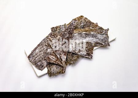 Laminaria japonica a secco（kelp）Isolata su fondo bianco. Kombu alghe, tradizionale ingrediente giapponese per cucinare la zuppa Dashi, copia spazio Foto Stock