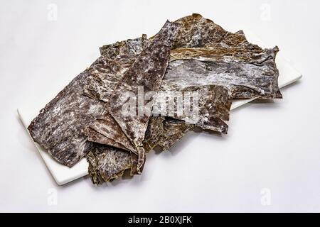 Laminaria japonica a secco（kelp）Isolata su fondo bianco. Kombu alghe, tradizionale ingrediente giapponese per cucinare la zuppa Dashi, copia spazio Foto Stock