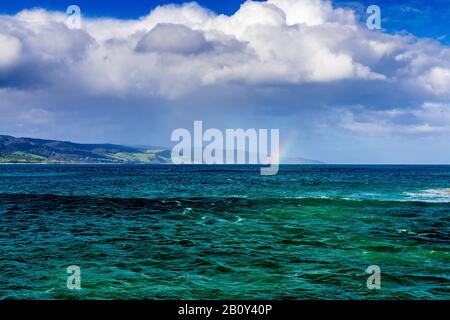 Apollo Bay con la pioggia che si avvicina causando la formazione di un piccolo arcobaleno sull'acqua. Victoria, Australia Foto Stock