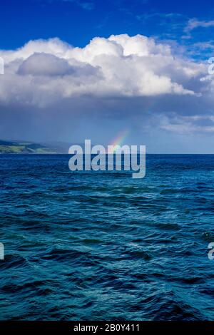 Apollo Bay con la pioggia che si avvicina causando la formazione di un piccolo arcobaleno sull'acqua. Victoria, Australia Foto Stock