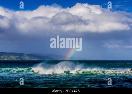 Apollo Bay con la pioggia che si avvicina causando la formazione di un piccolo arcobaleno sull'acqua. Victoria, Australia Foto Stock